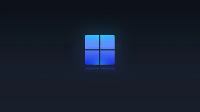 The blue Windows 11 square glows at the centre of a near-black navy field, its light falling off within a few inches of the logo.