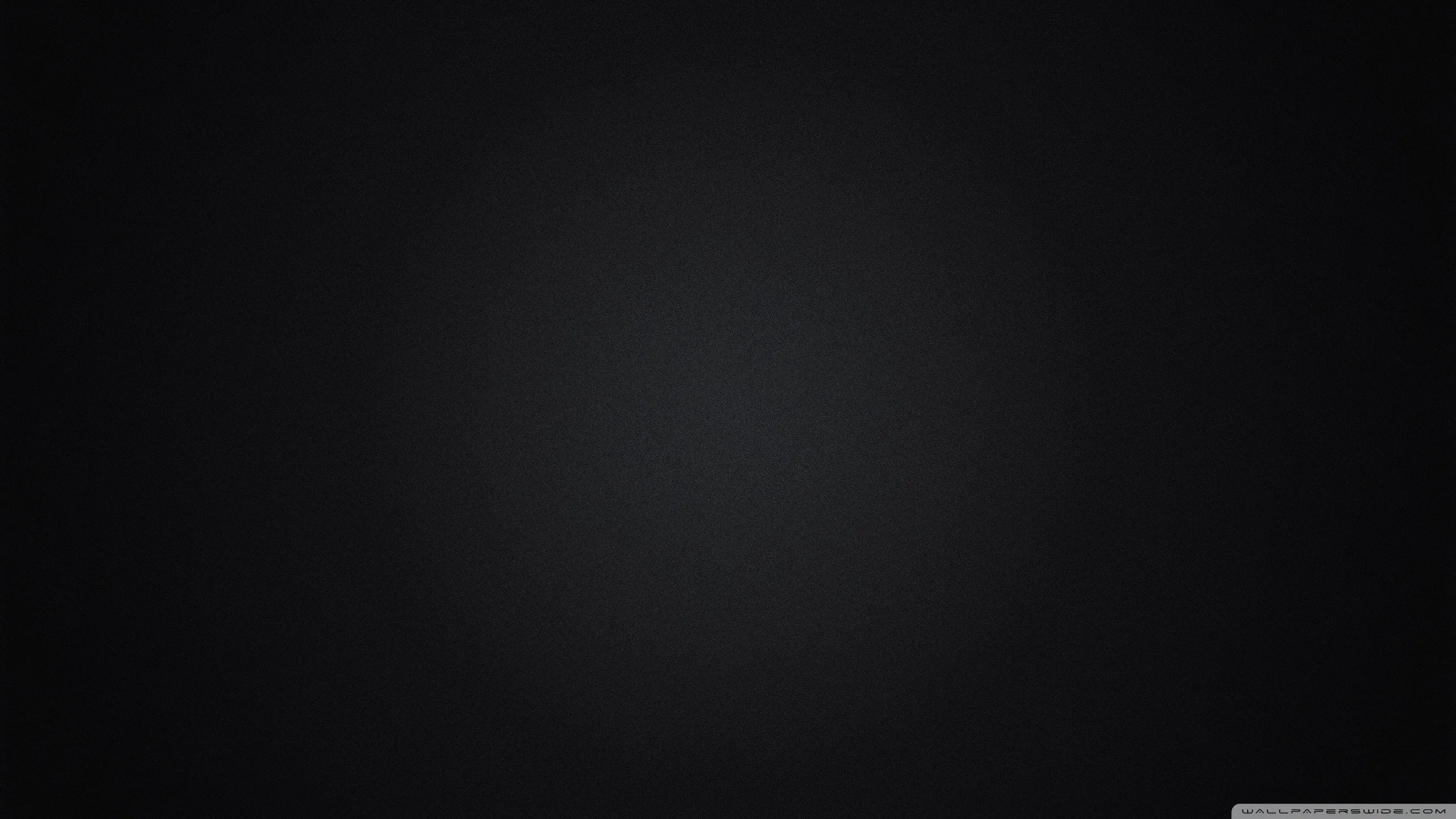 A plain dark backdrop with a faint lift of grey through the centre, falling away evenly to black at the edges.