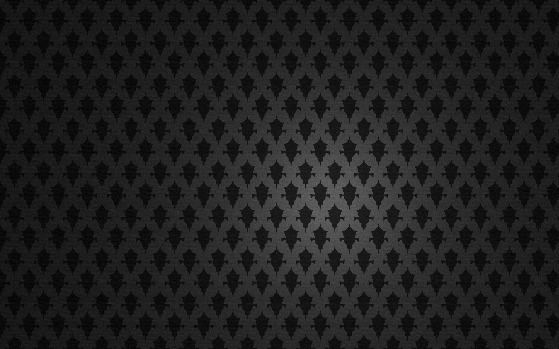 A tiny repeating motif covers a charcoal field evenly, catching a faint highlight through the middle.