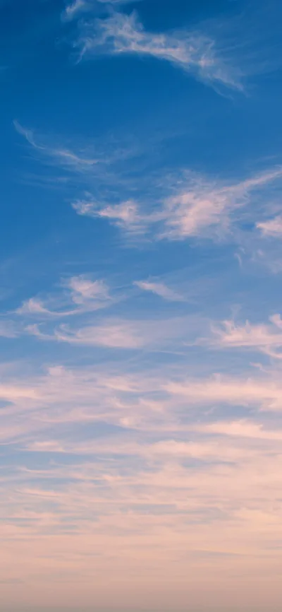 Thin pink cirrus streaks cross a blue evening sky, warming to pale peach near the bottom — a quiet backdrop that keeps app icons legible.
