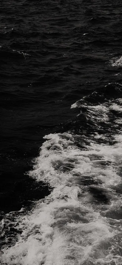 White foam trails diagonally across near-black sea, shot from above so the wake fills the lower half.