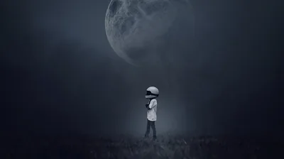 A child in a round helmet crosses a misty grey field while an oversized moon fills the top of the frame, the palette kept to soft monochrome blues.
