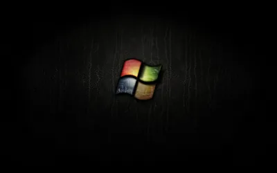 The four-colour window flag sits small at the centre of a scratched dark wood surface.