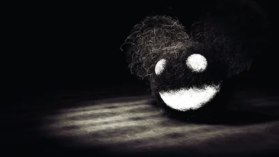 A shaggy round mouse head with wide white eyes and a grin sits in a single overhead beam, the floor around it fading into dark.