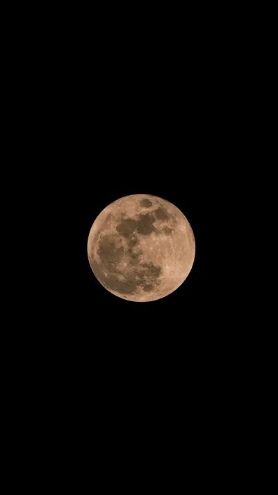 A warm orange moon sits alone against true black, small in the frame so most of the screen stays fully dark on OLED.