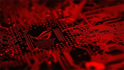 The ASUS Republic of Gamers eye glows above a motherboard packed with chips and traces, everything washed in hard red light.