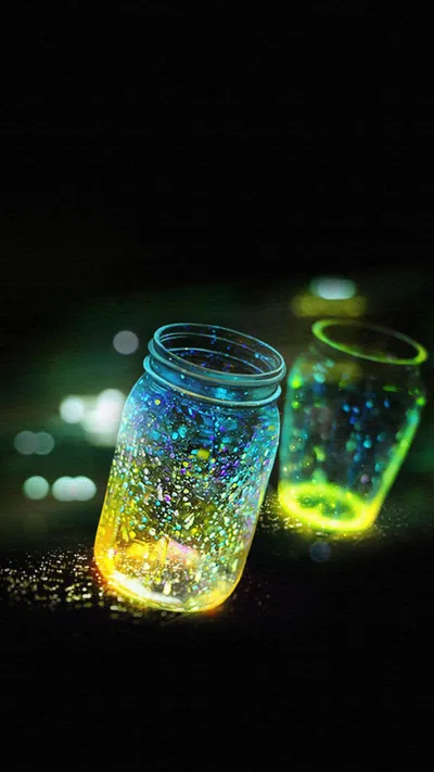 Two glass jars sit on dark ground filled with blue and yellow points of light, small bokeh circles scattered behind them.