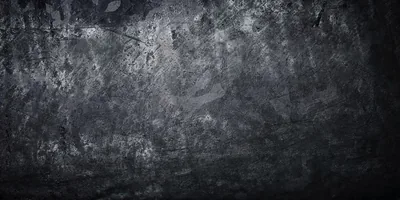 A mottled charcoal surface with scuffs and pale patches through the middle, darkening steadily toward all four corners.