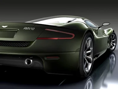 The tail of a dark green Aston Martin concept sits on a mirror-black floor, its slim rear lamp and round exhaust tip the brightest points in frame.