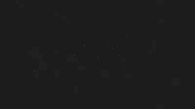 A near-black charcoal surface scattered with tiny pale specks, evenly lit so nothing pulls the eye toward any one corner.
