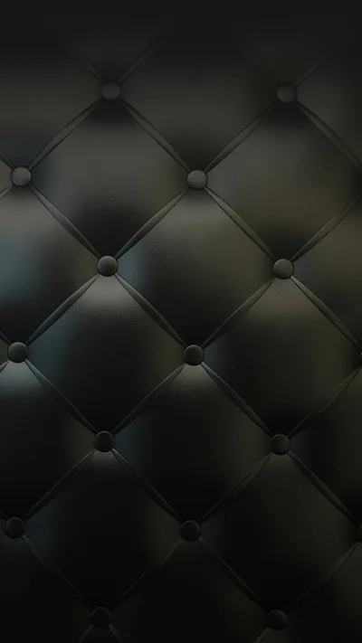 Buttoned tufting pulls dark leather into a diamond grid, a faint blue-green sheen catching along the upper folds.