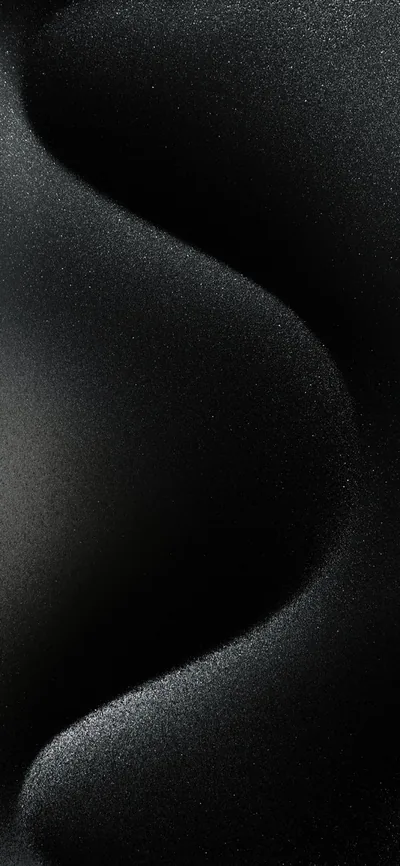 Smooth S-curves of fine grainy sand fill the frame, the ridges lit softly from the left so the grain reads without lifting the black.