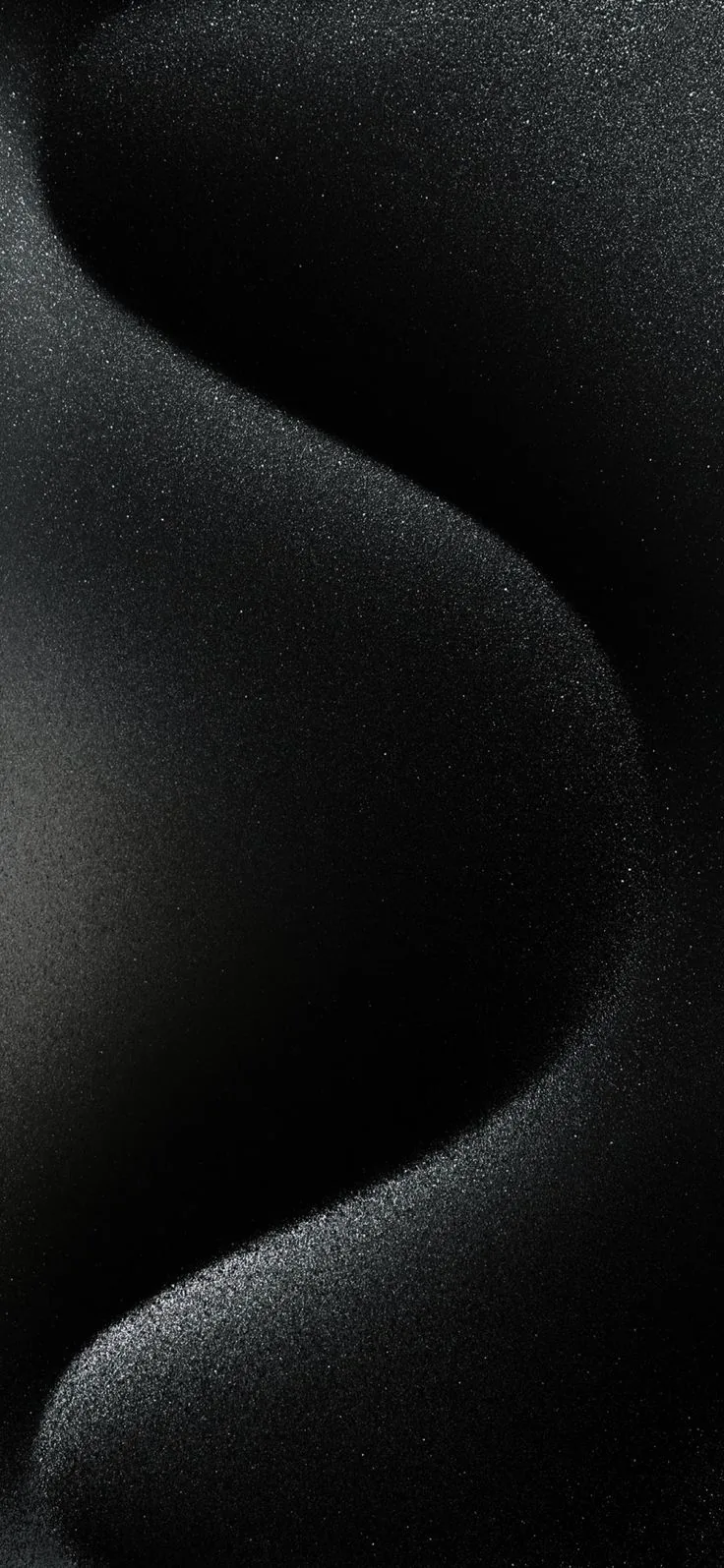 Smooth S-curves of fine grainy sand fill the frame, the ridges lit softly from the left so the grain reads without lifting the black.