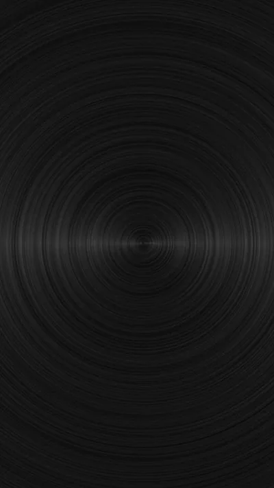 Turned rings spread from a bright pinpoint at the centre of dark metal, the grain catching light in a thin band across the middle.