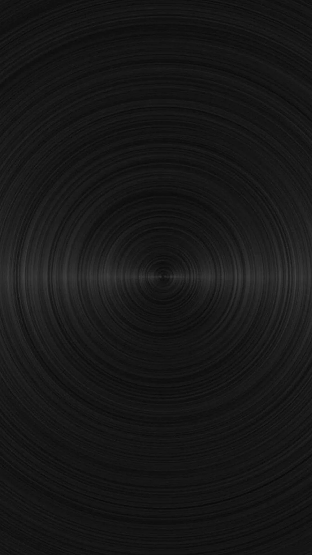 Turned rings spread from a bright pinpoint at the centre of dark metal, the grain catching light in a thin band across the middle.