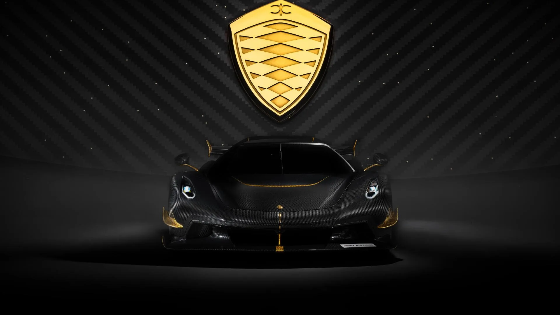 The Jesko faces the camera dead centre with the gold shield emblem hanging above it, gold trim on the splitter and mirrors the only warm notes in a black room.